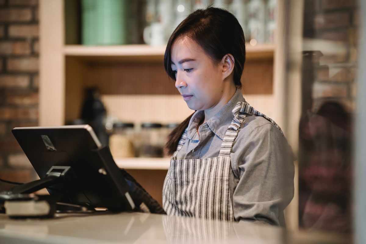 お店のレジ端末を操作する女性スタッフ