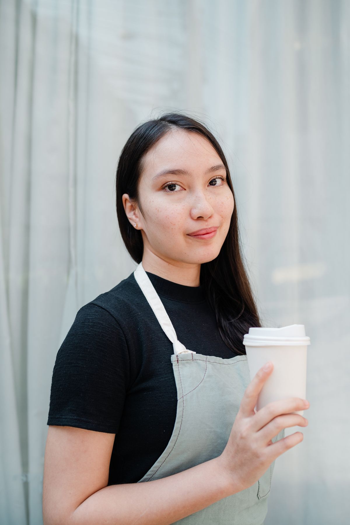 エプロン姿でドリンクを手にするお店の女性スタッフ